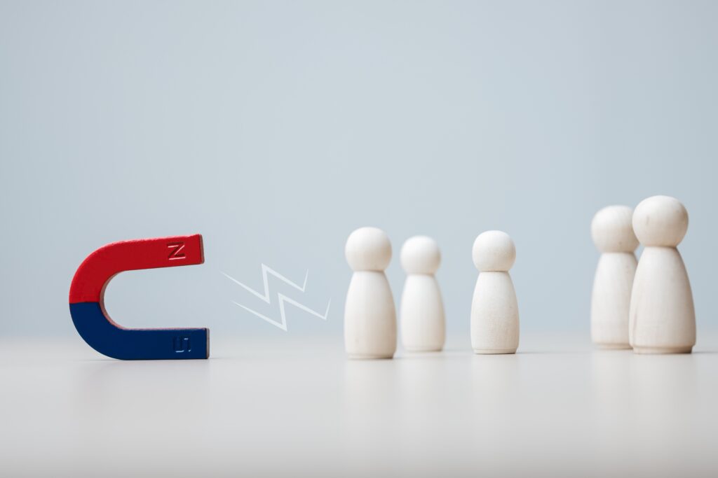 A magnet attracting five wooden figures symbolizing customer retention