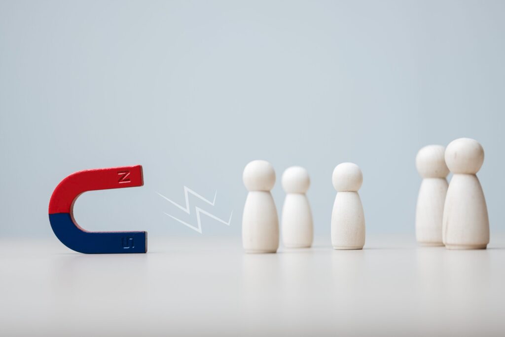 A magnet attracting five wooden figures symbolizing customer retention