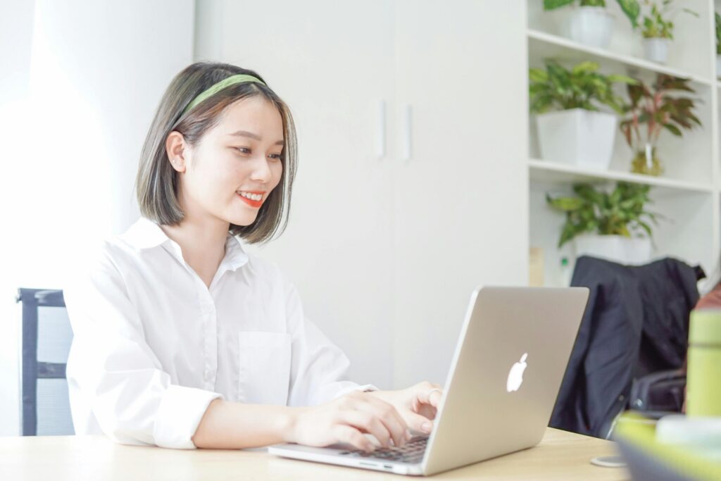 A young woman working on her laptop at a desk, exploring entry-level marketing careers.