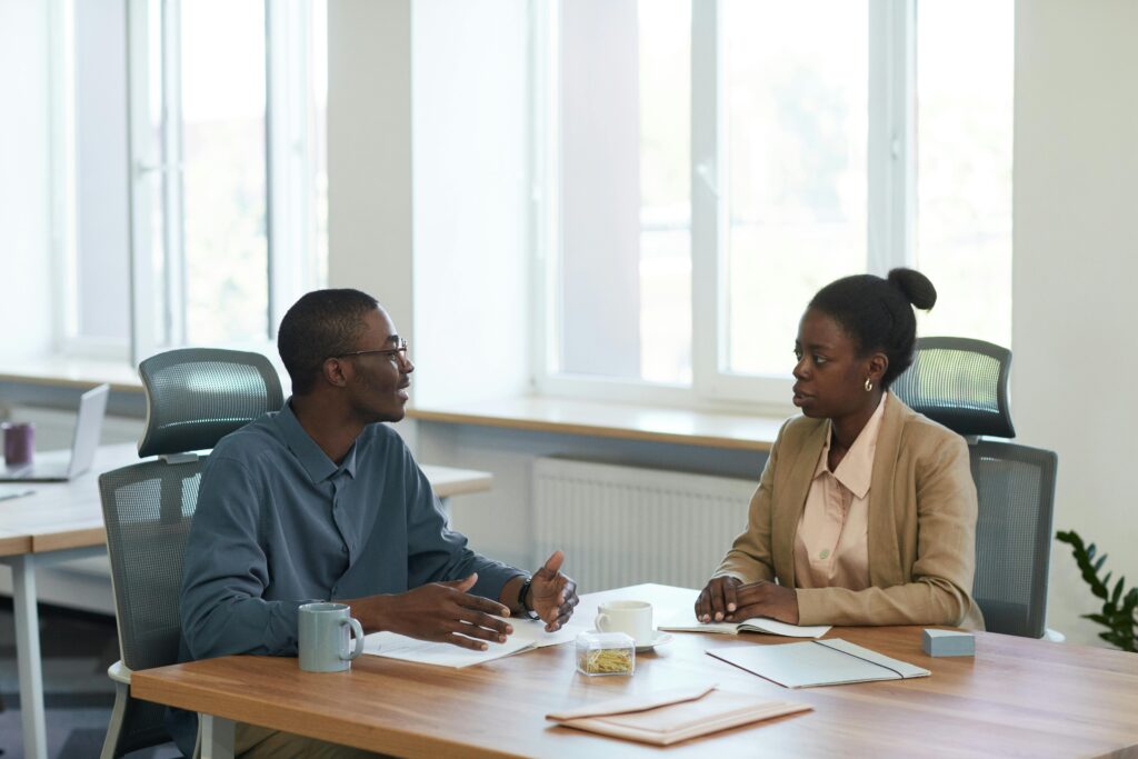 Two colleagues in a meeting room giving peer feedback to each other.