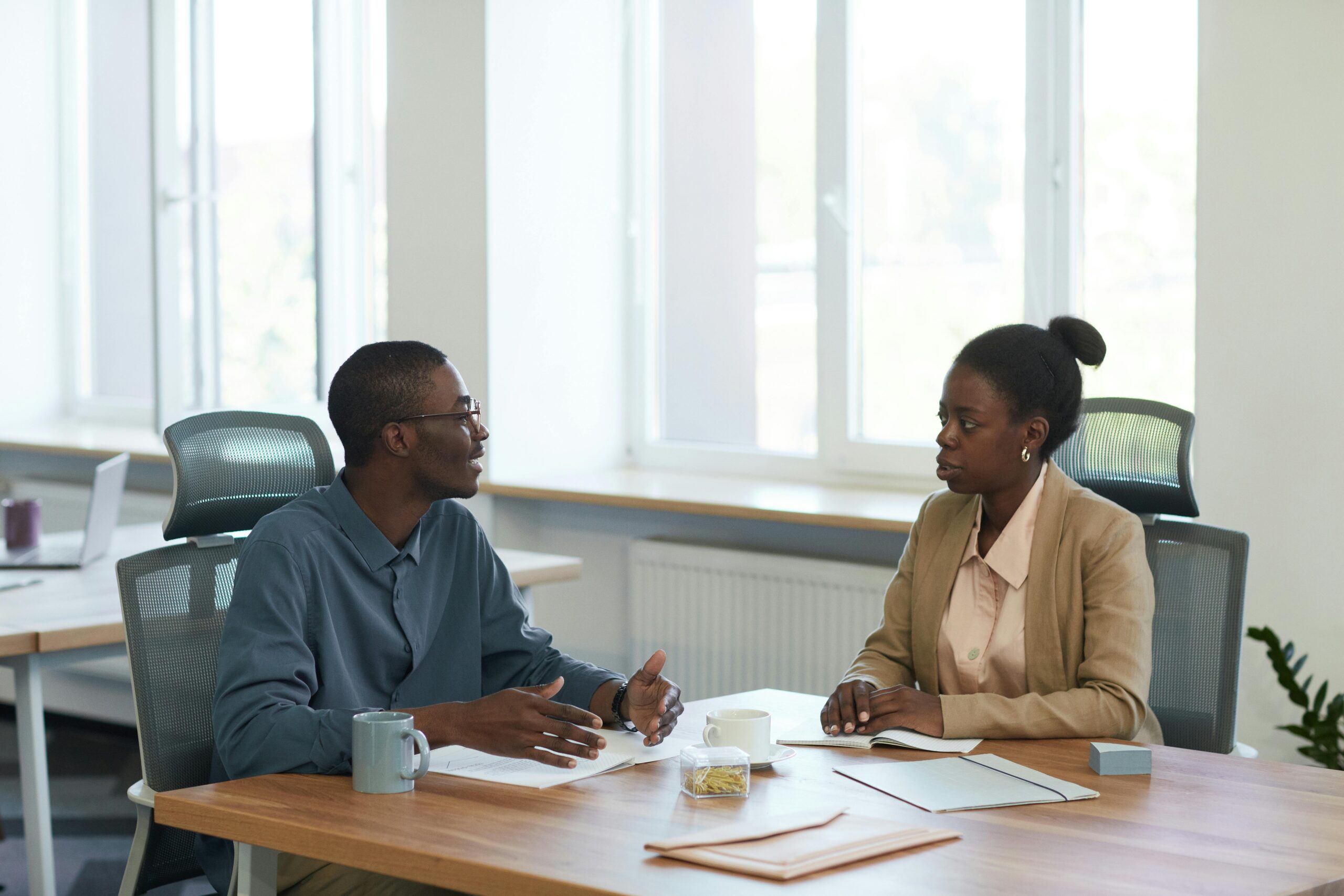 Two colleagues in a meeting room giving peer feedback to each other.
